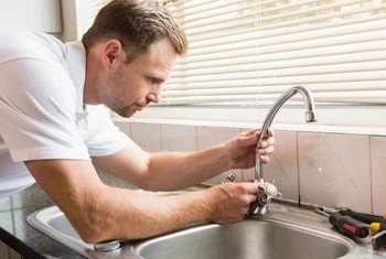 About People Helping People plumber repairing a kitchen faucet