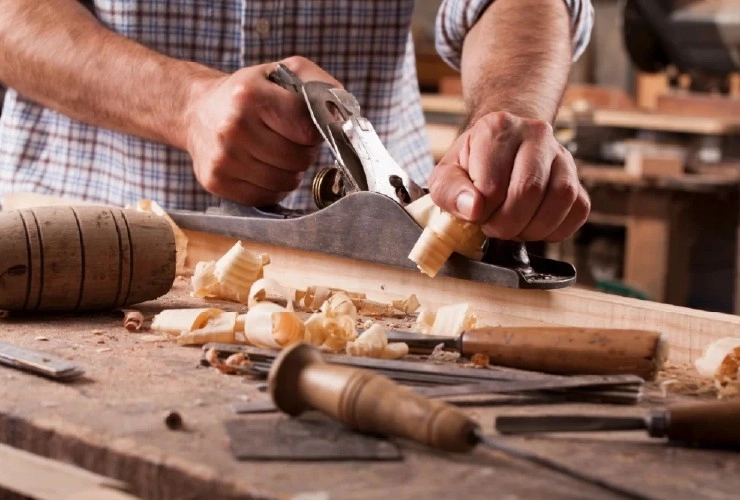 About People Helping People carpenter planing wood by hand