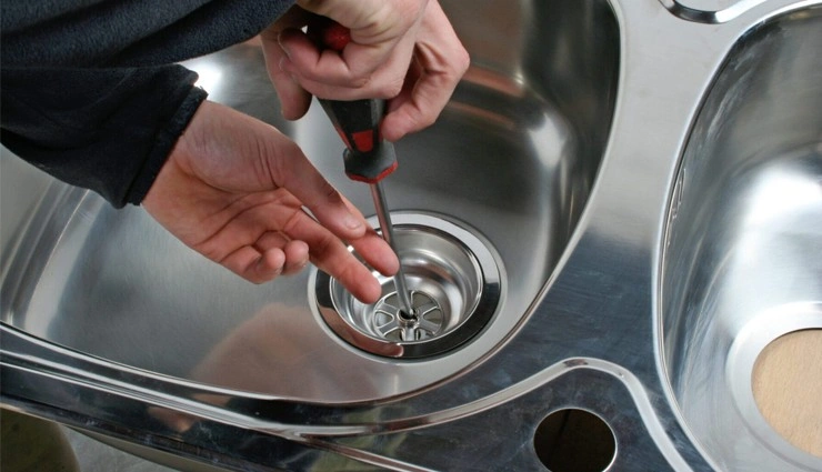 About People Helping People fixing a stainless steel sink drain