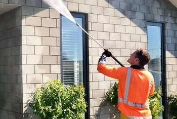 About People Helping People worker cleaning stone house wall