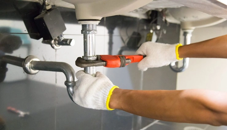 About People Helping People plumber tightening pipes under a sink